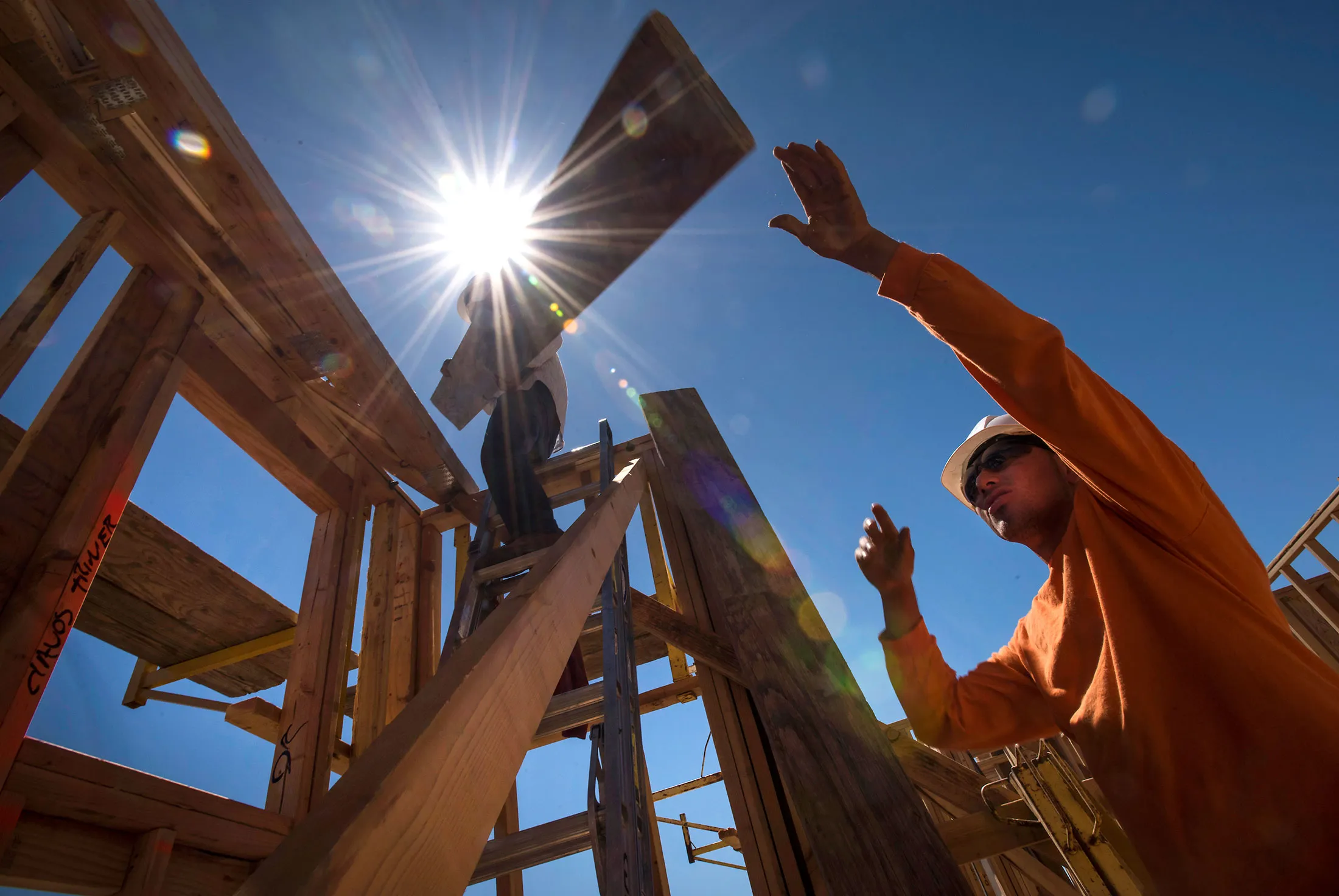 Workers load wood planks on a house under construction in Livermore, California.
