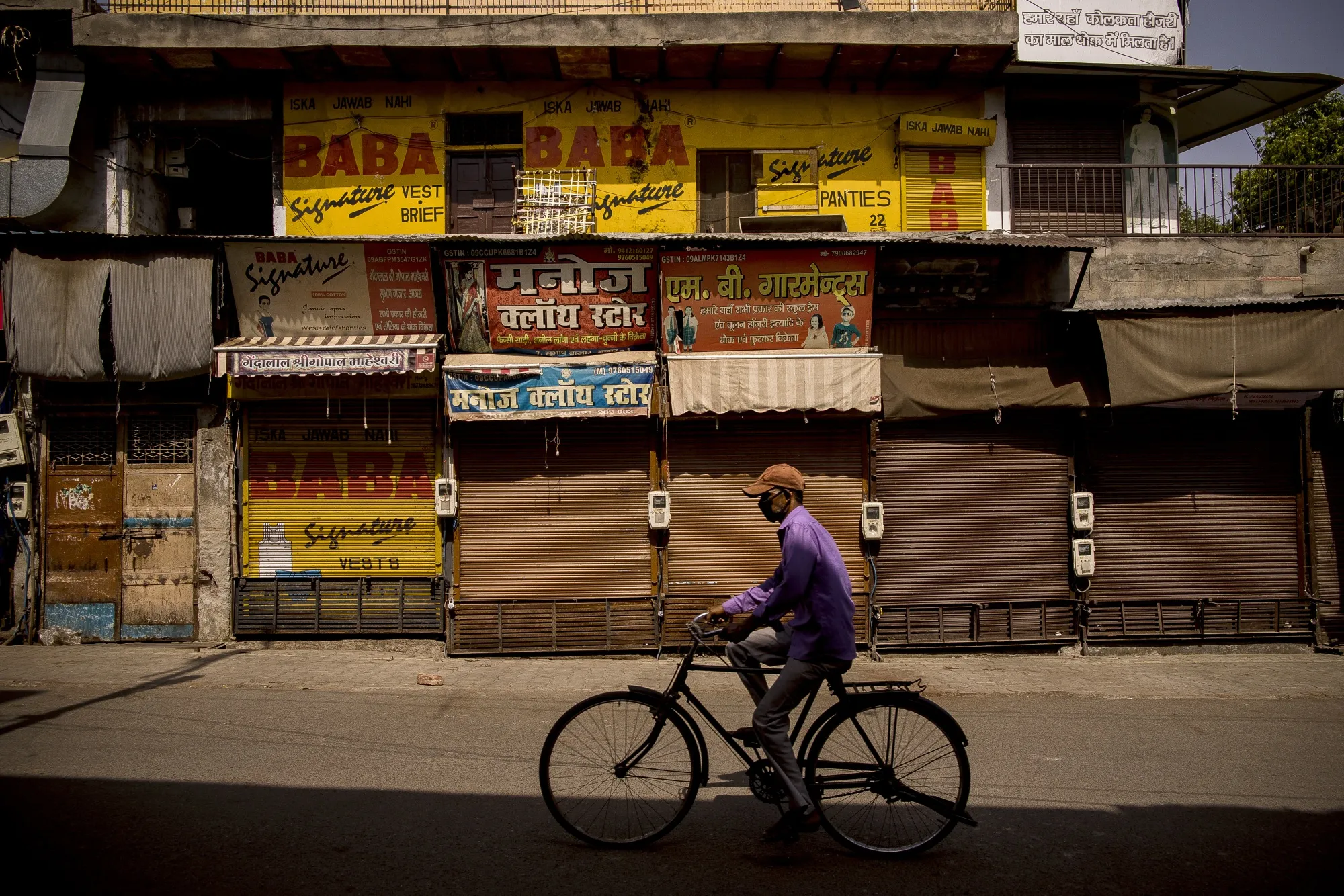 A cyclist passes closed stores in Agra, India on&nbsp;June 6.