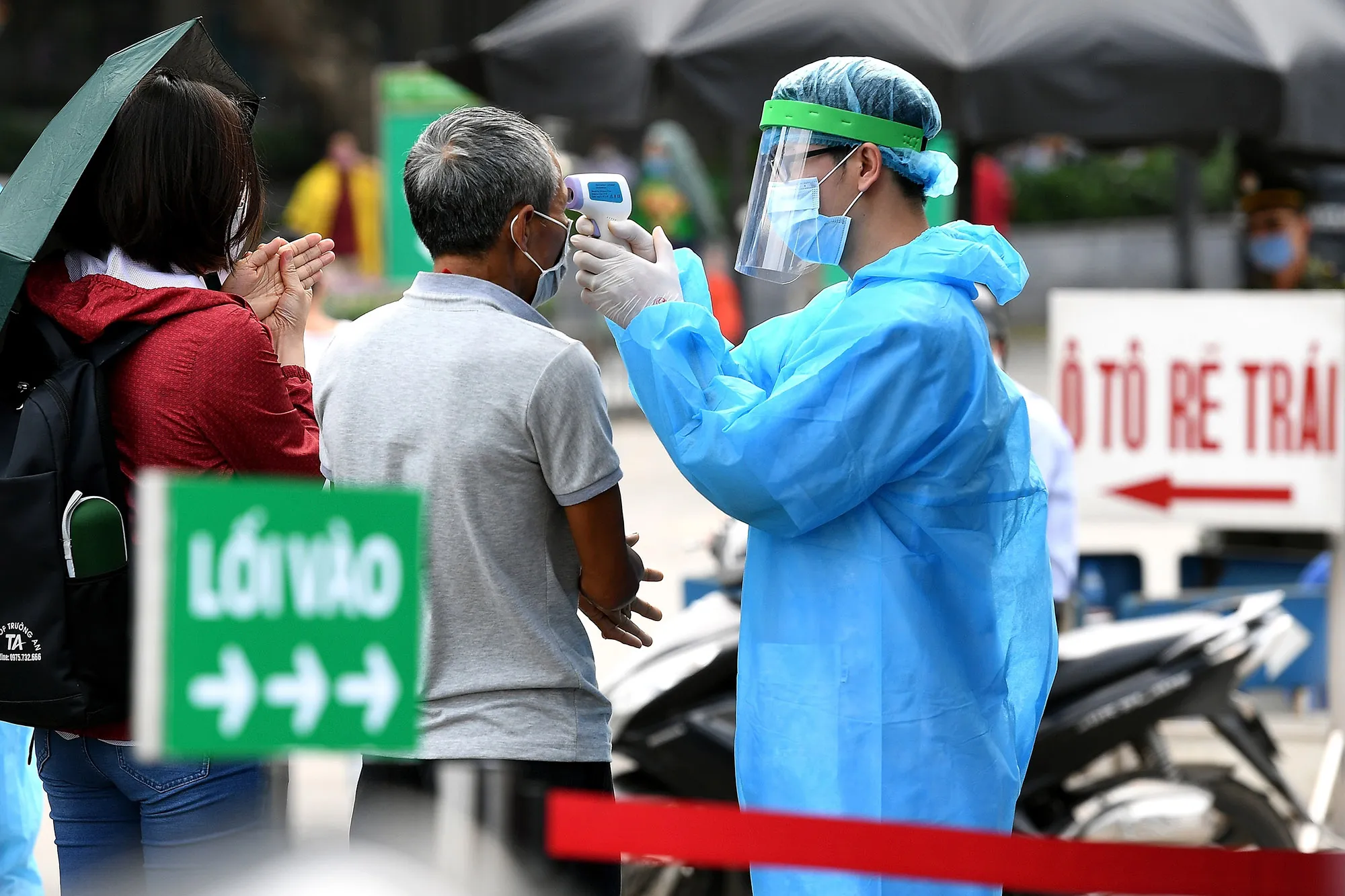 A health worker checks temperatures of visitors at the entrance of Bach Mai hospital in Hanoi on March 24.
