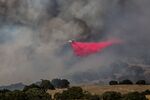 A Cal Fire aerial attack plane drops Phos-Chek fire retardant on a fast-moving 200 acre brushfire (The McMurray Fire) after it closed Highway 101 and spread across the ranch and vineyard hillsides triggering some evacuations on September 9, 2019, just north of Buellton, California.