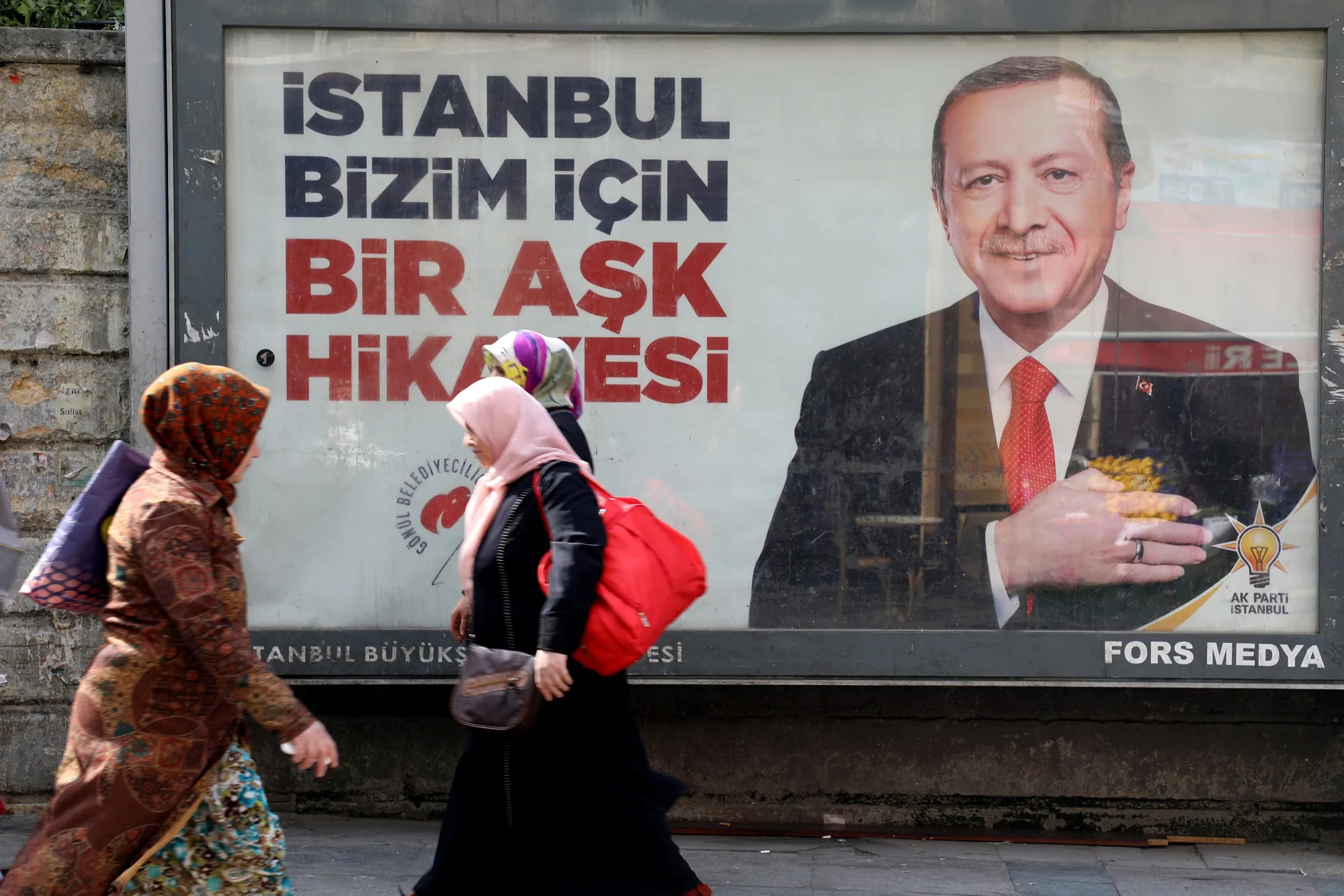 Pedestrians pass a campaign banner featuring President Recep Tayyip Erdogan on a street in Istanbul, Turkey, on March 28, 2019. 