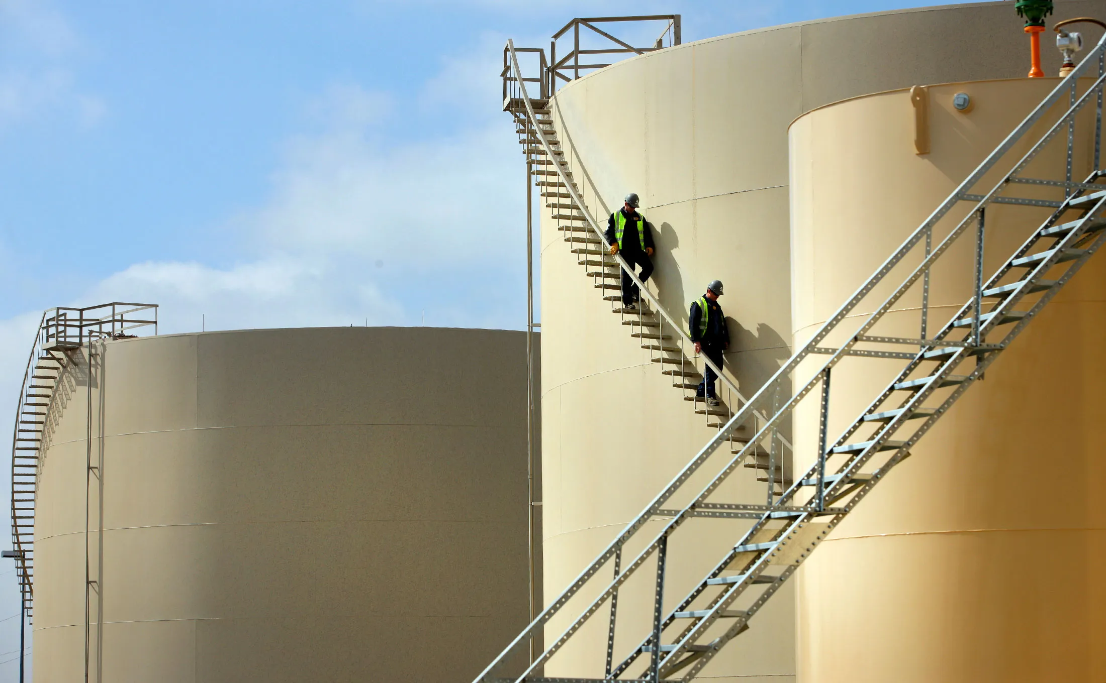 Two men stand on storage tanks during a tour of the Musket Corporation Windsor Terminal (a truck to rail facility) in Windsor, Colorado, U.S., on Wednesday, April 2, 2014.
