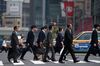 Office workers walk across an intersection in Tokyo, Japan.