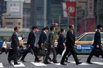 Office workers walk across an intersection in Tokyo, Japan.