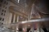 Pedestrians are reflected in a puddle while passing in front of the New York Stock Exchange (NYSE) in New York, U.S., on Friday, Feb. 16, 2018. U.S. equities headed for the best week in six years as the rebound in global equities pushed into a sixth day. The dollar strengthened after a five-day selloff and Treasuries climbed.