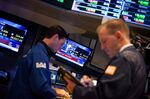 A television screen displays news about the Dow Jones Industrial Average reaching 26,000 while traders work on the floor of the New York Stock Exchange (NYSE) in New York, U.S., on Tuesday, Jan. 16, 2018.