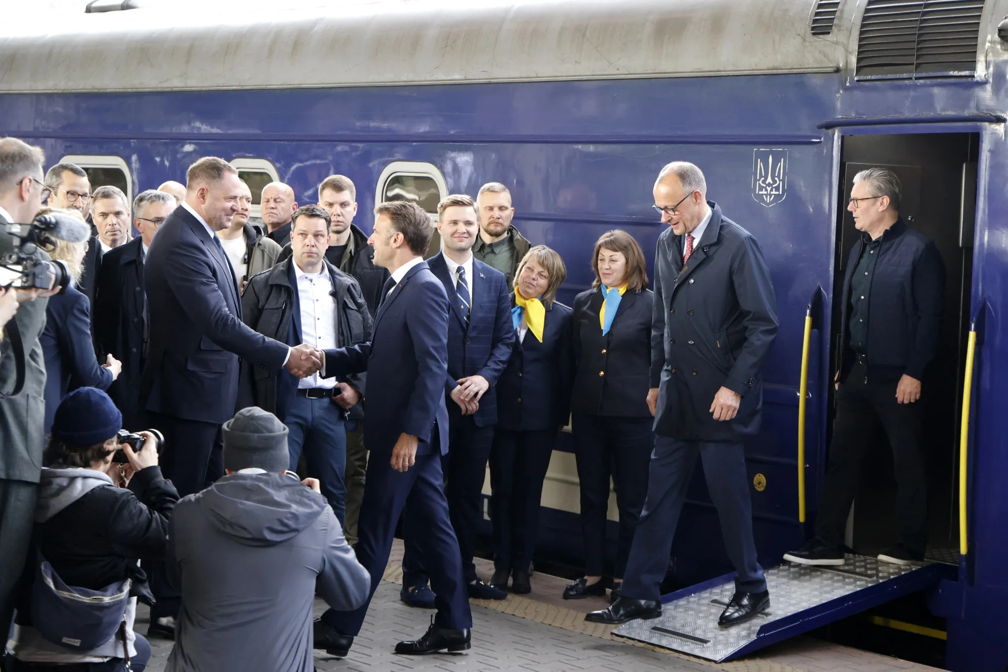 An official greets Emmanuel Macron, Friedrich Merz and Keir Starmer as they arrive at Kyiv railway station on May 10.