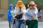 Pedestrians cover up amid high temperature in Chongqing, on July 13.