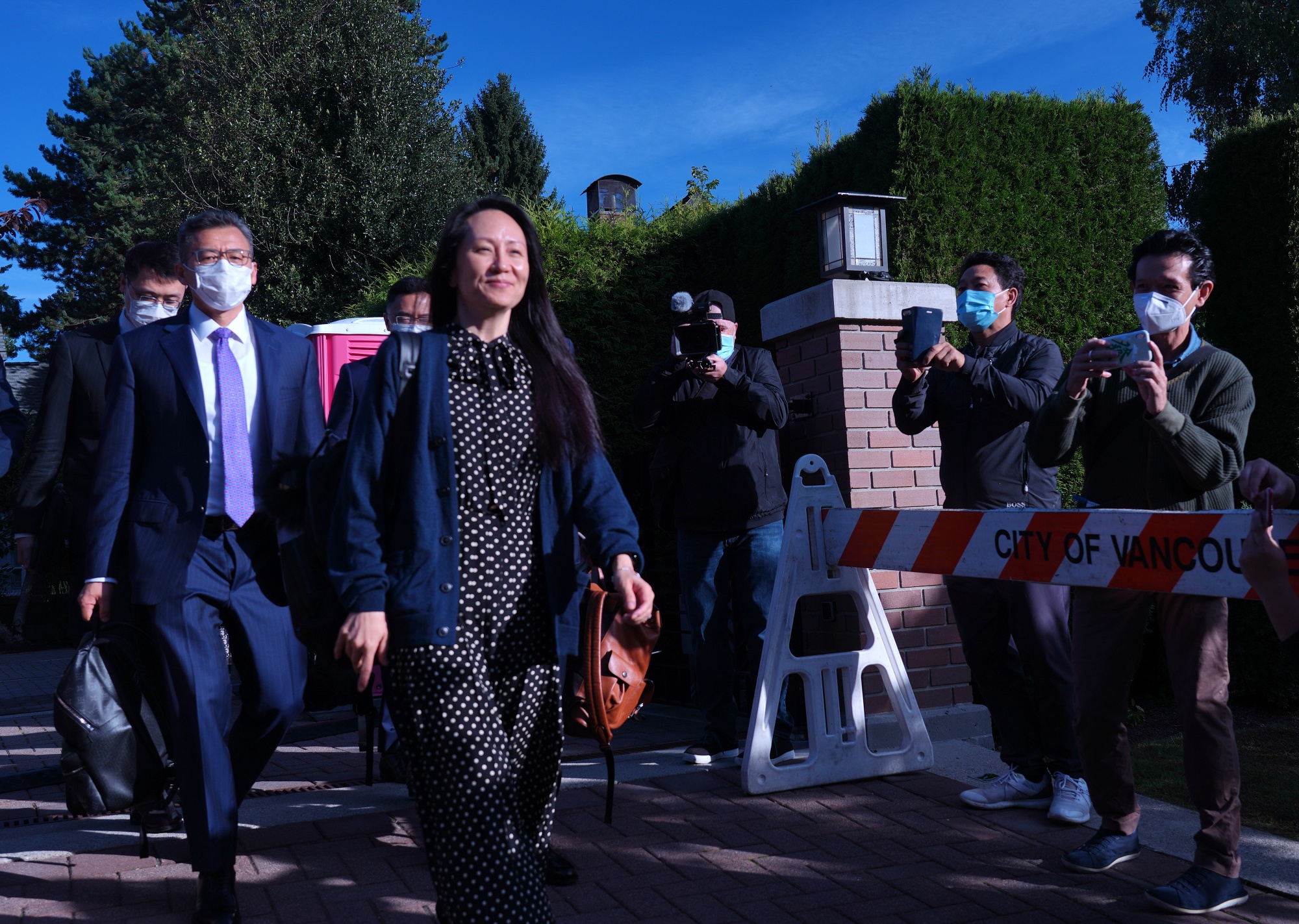 Meng Wanzhou, center, exits her home in Vancouver, on Sept. 24.