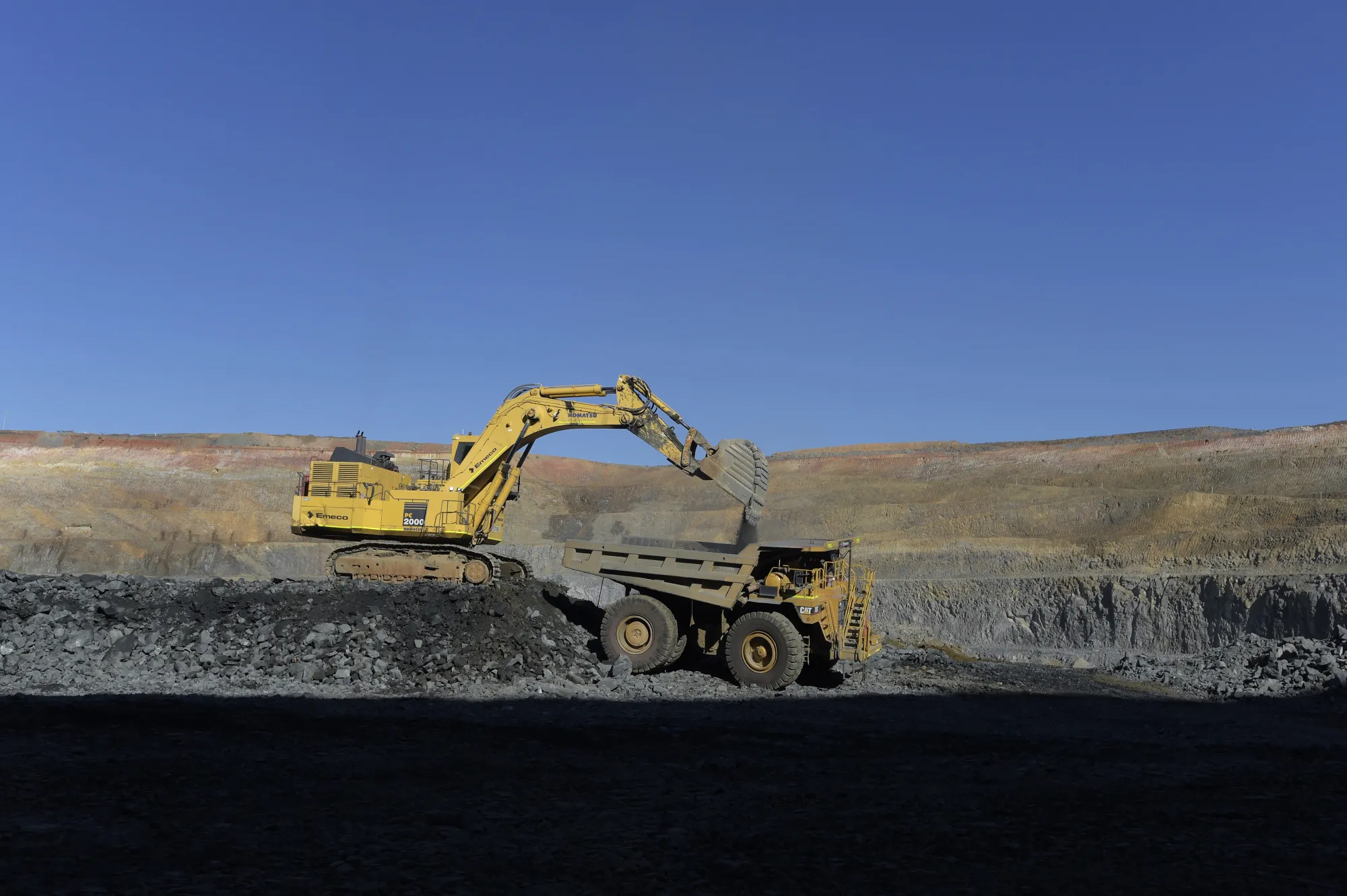 An excavator deposits ore into a dump truck in the White Foil open mine pit at Evolution Mining Ltd.'s gold operations in Mungari, Australia, on Tuesday, Aug. 8, 2017. Evolution Mining is Australia’s second-largest gold producer.