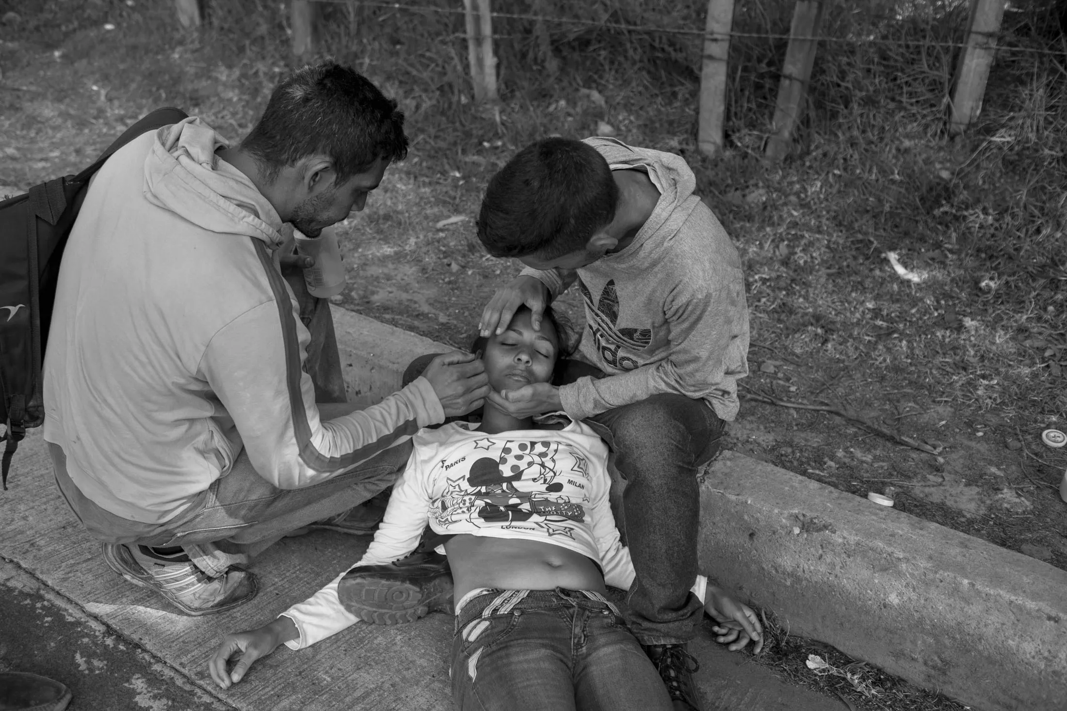 Richard and Hector, migrants we followed for days, attend to a fellow migrant who fainted.