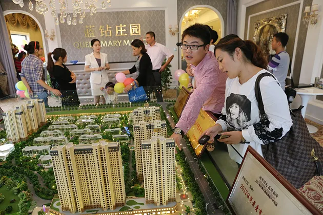 Chinese home buyers look at models of residential apartment buildings at a real estate fair in Linyi, China, on Oct. 1