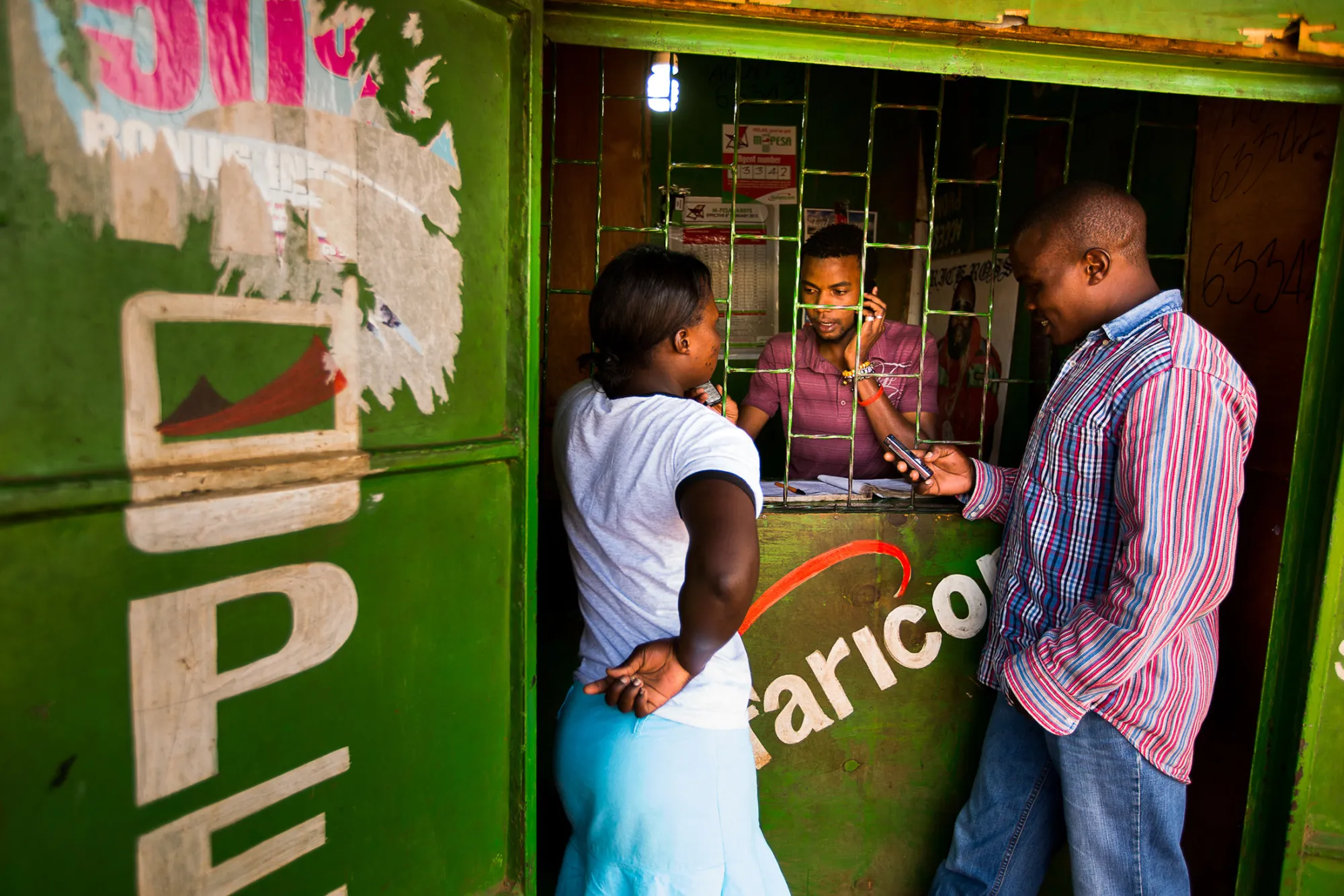Residents transfer money using the M-Pesa banking service at a store in Nairobi, Kenya, on Sunday, April 14, 2013. In the six years since Kenya's M-Pesa brought banking-by-phone to Africa, the service has grown from a novelty to a bona fide payment network.
