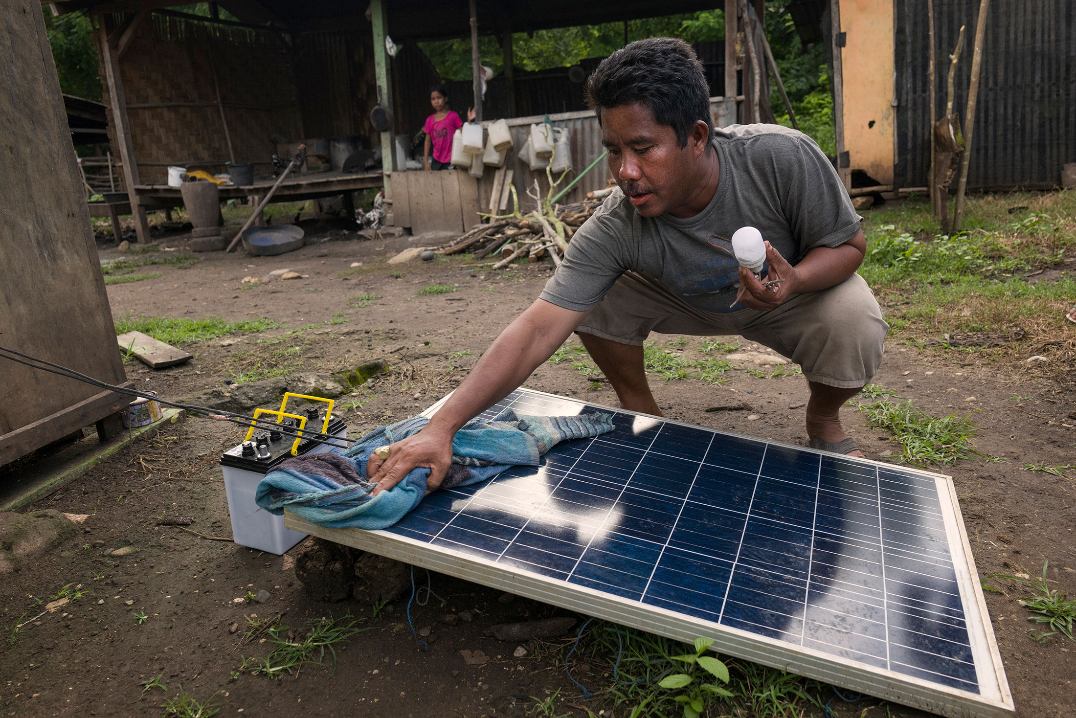 Joshua Pekuali cleans a mini solar panel he uses for lights at his home and shop
