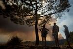 Residents look at smoke columns rising from a wildfire in Sierra Bermeja mountain range in Benahavis, Malaga province, on Sept. 9.
