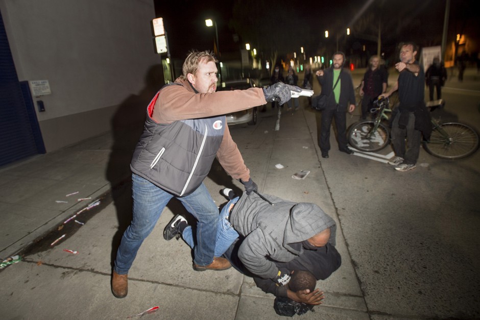 An undercover agent pulls a firearm on protesters in Oakland on December 10.
