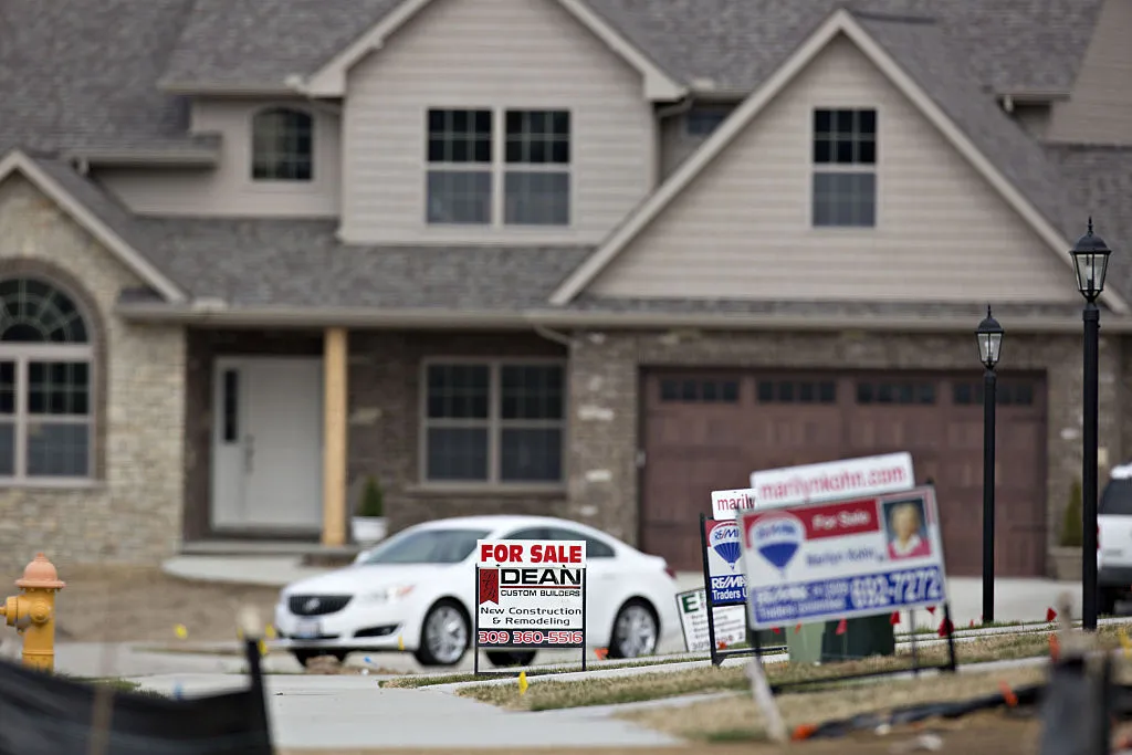 A "For Sale" sign stands outside a new home.