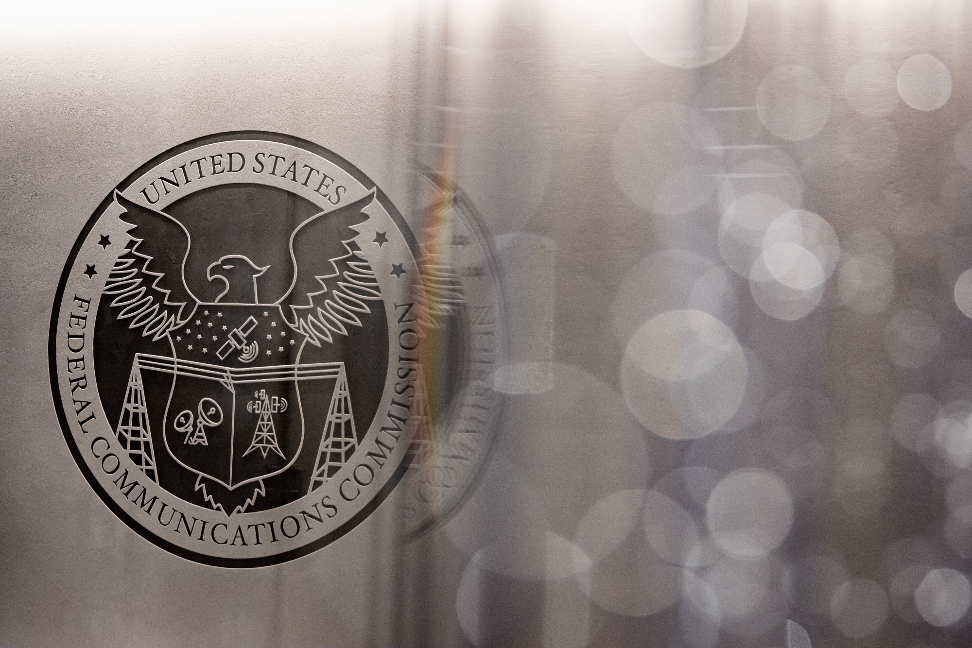 The seal of the Federal Communications Commission (FCC) prior to an open commission meeting at the agency's headquarters in Washington, DC, US, on Wednesday, Feb. 18, 2026. Federal Communications Commission Chairman Brendan Carr sees legitimate competition concerns in Netflix Inc.'s proposed acquisition of Warner Bros. Discovery Inc.'s studios and streaming businesses, concerns he doesn't share if Paramount Skydance Corp. were to acquire those assets. Photographer: Al Drago/Bloomberg