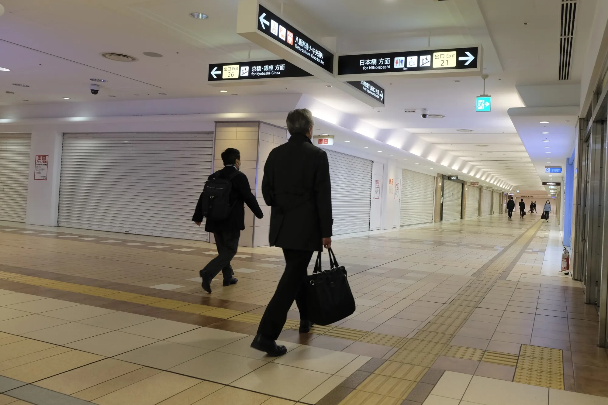 Commuters walk past closed shops in an underground shopping mall in Tokyo railway station on April 15.