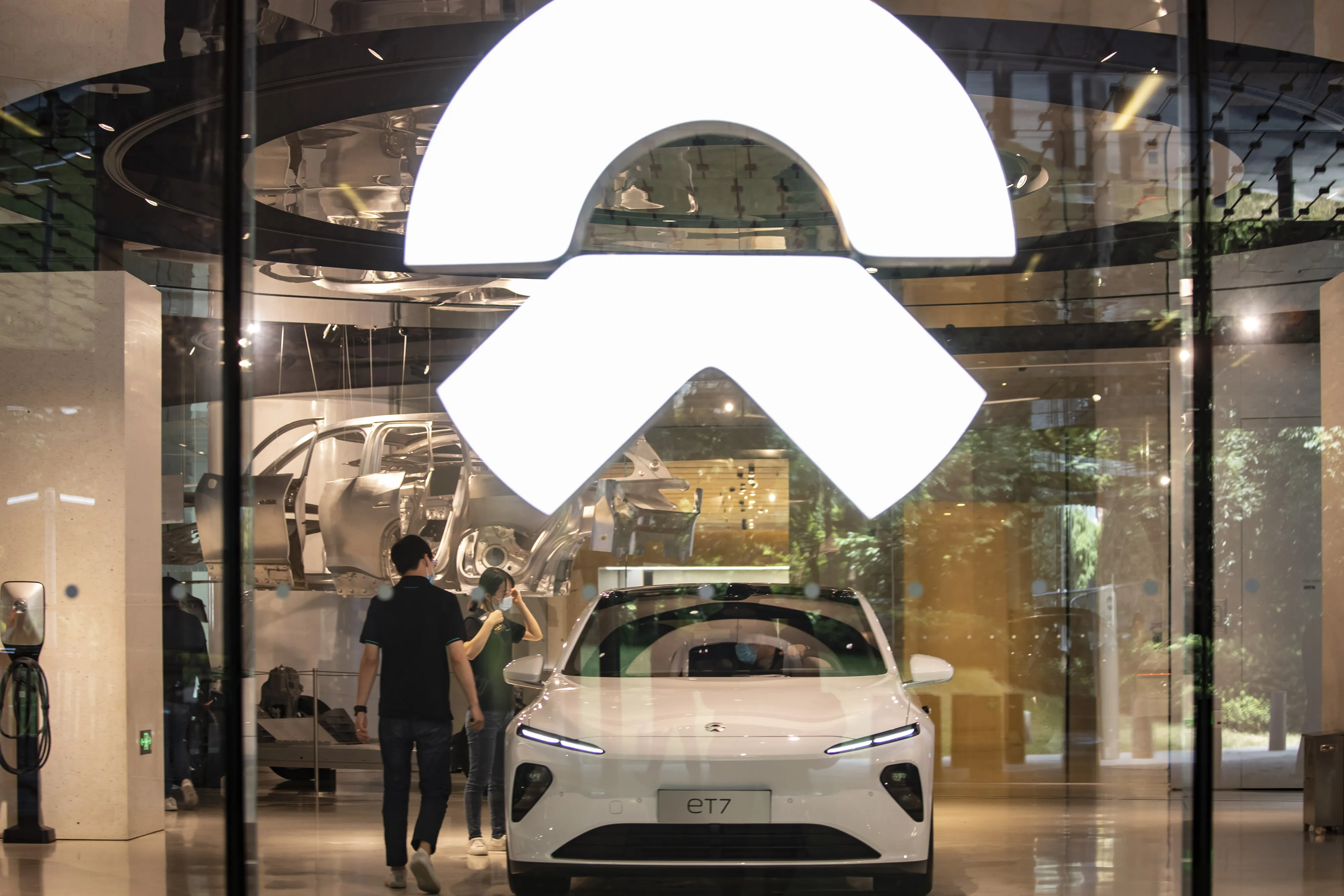 Employees stand next to a ET7 sedan at a NIO Inc. dealership in Shanghai.