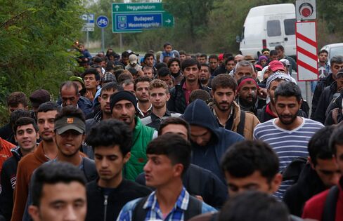 Migrants set off on foot after Austrian authorities suspended train service due an overload of the train system at the Austrian border, near Hegyehshalom, Hungary on Sept. 11. Photographer: Win McNamee/Getty Images