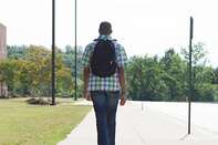Male high school student walking along pavement