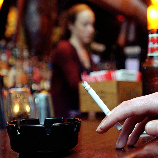 A patron of a bar in the neighborhood of Soho holds a cigarette March 28, 2003 in New York City.