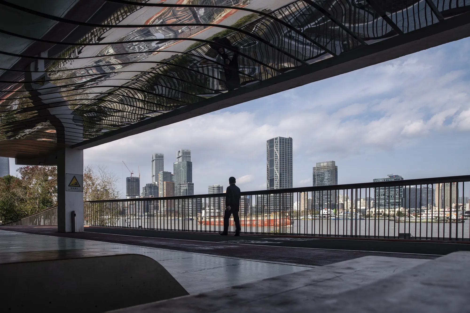 A pedestrian walks on a riverside path near the Lujiazui financial district in Shanghai.