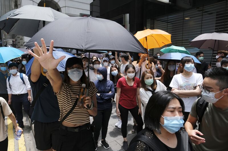 Demonstrators raise their hands to gesture the "Five demands, not one less" protest motto in the Central district during a protest in Hong Kong, China, on Wednesday, May 27, 2020. 