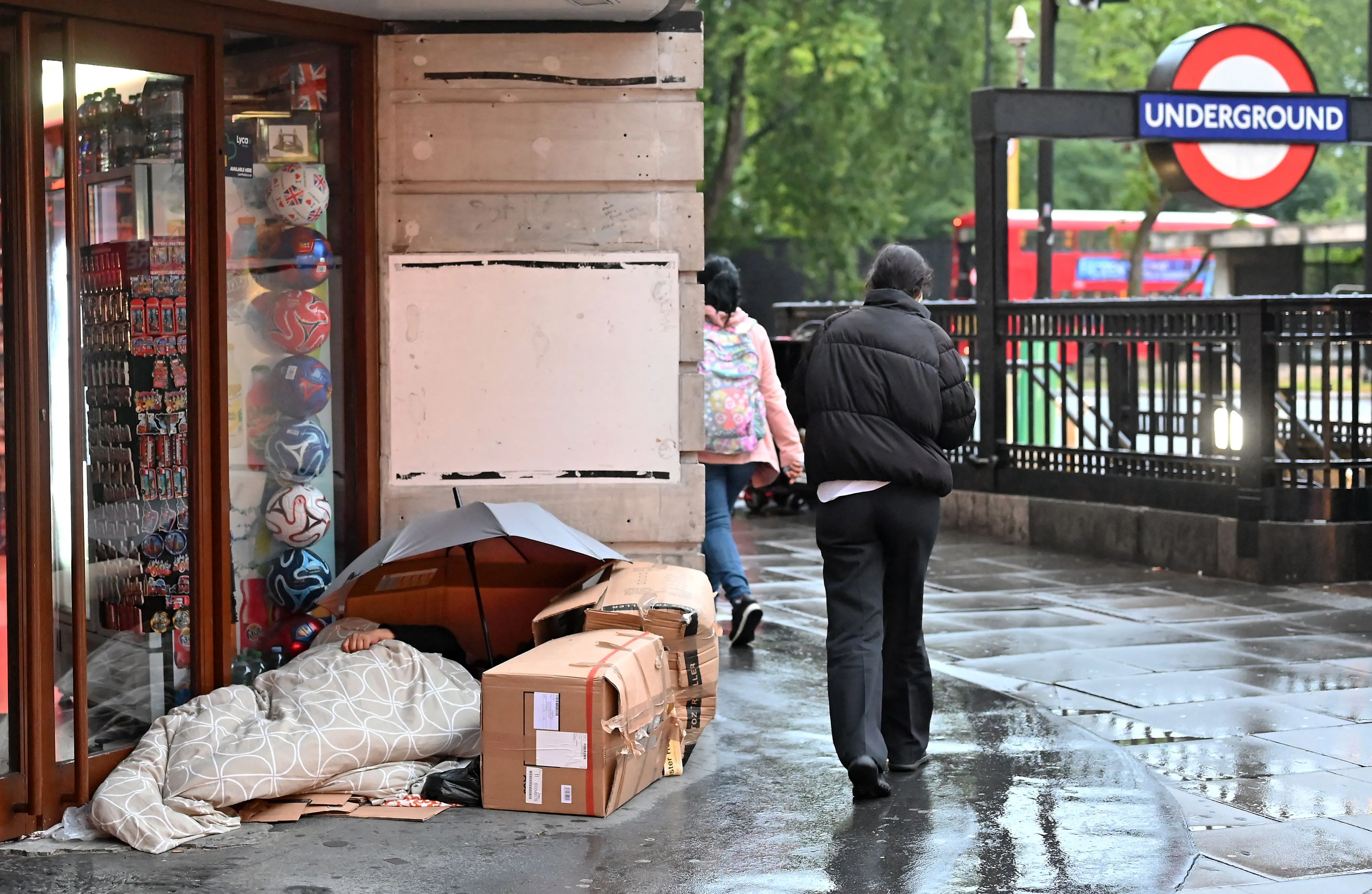 A pedestrian walks past an unhoused person in their makeshift bed&nbsp;in London.&nbsp;