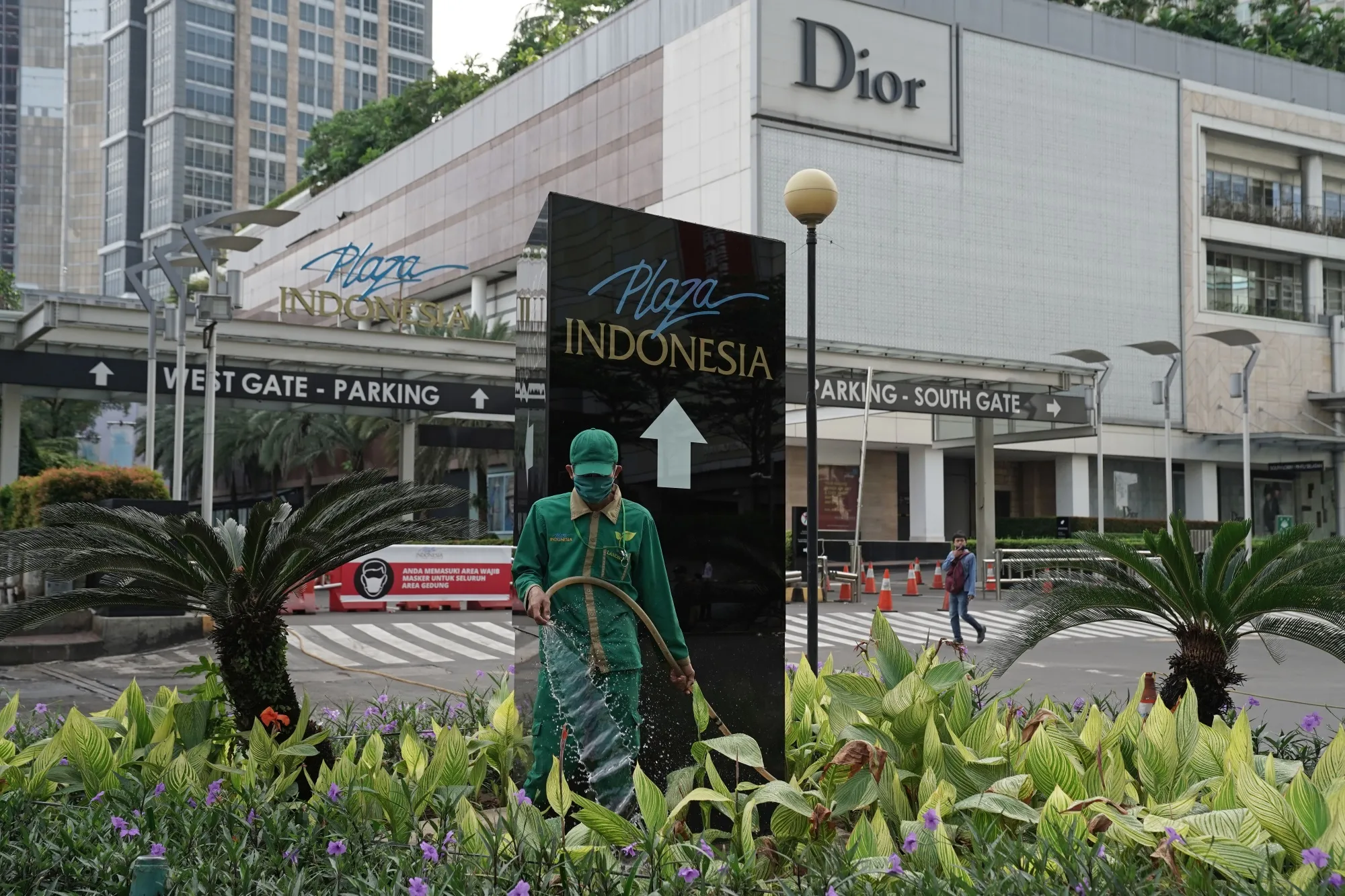 A worker wearing a protective mask waters the plants outside the Plaza Indonesia shopping mall during a partial lockdown imposed due to the coronavirus in Jakarta on May 27.
