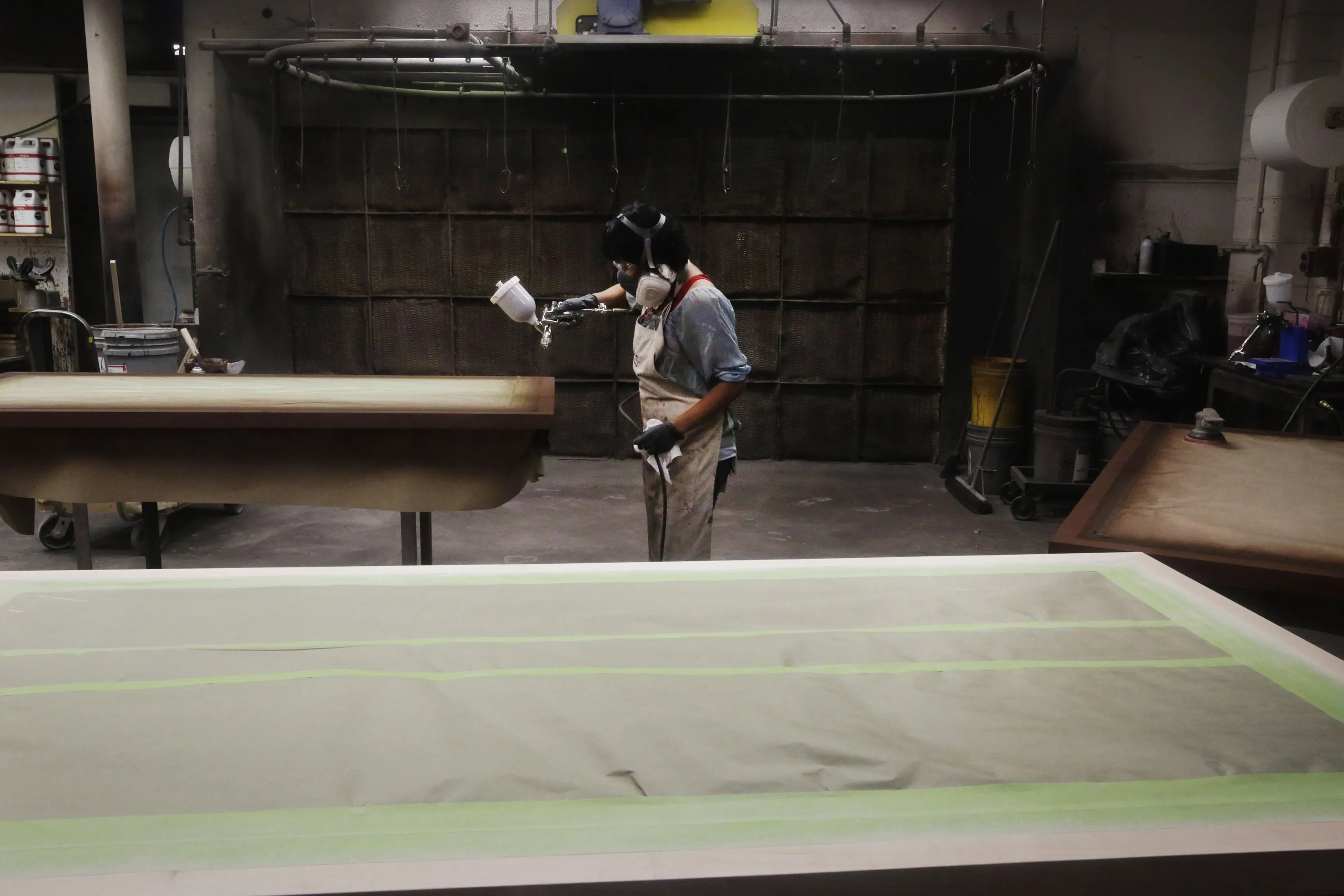 A worker stains a table top at a furniture manufacturing facility in Bend, Ore.