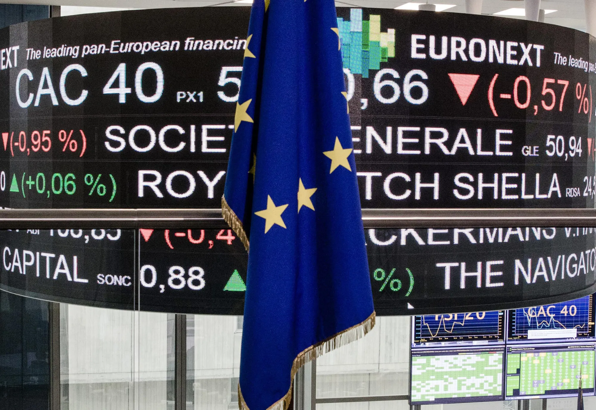 A European Union (EU) flag hangs in front of a board displaying company stock price information inside the Paris stock exchange, operated by Euronext NV, in La Defense business district in Paris, France, on Monday, May, 8, 2017. Emmanuel Macron pledged to heal France’s rifts after his victory over Marine Le Pen in the presidential election, saying that he’ll work to address the concerns that were exposed during one of the most divisive campaigns of recent history.
