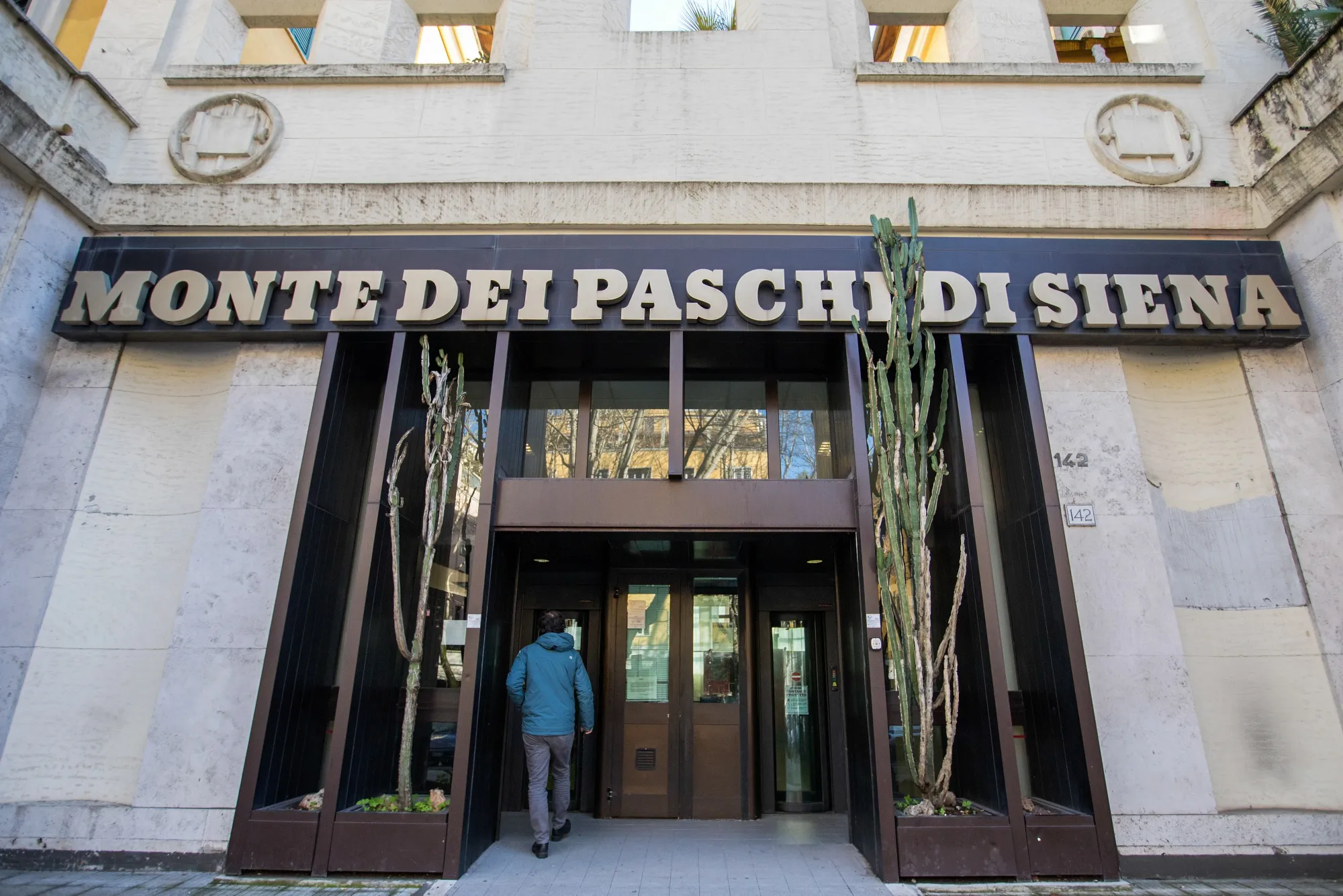 A pedestrian enters a Banca Monte dei Paschi di Siena SpA bank branch in Rome.