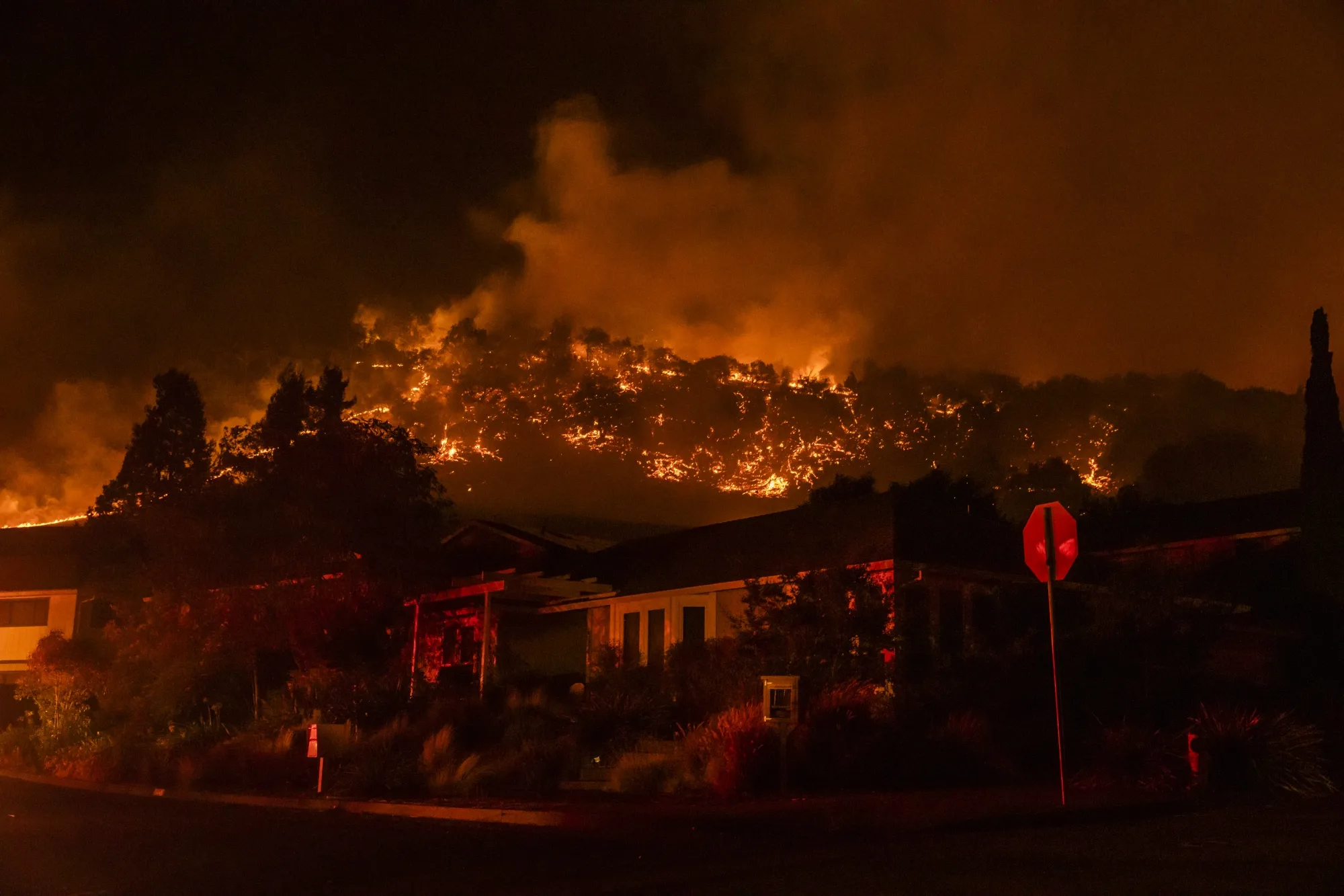 Fire burns over a ridge behind houses in&nbsp;Sonoma County, California, in September 2020.