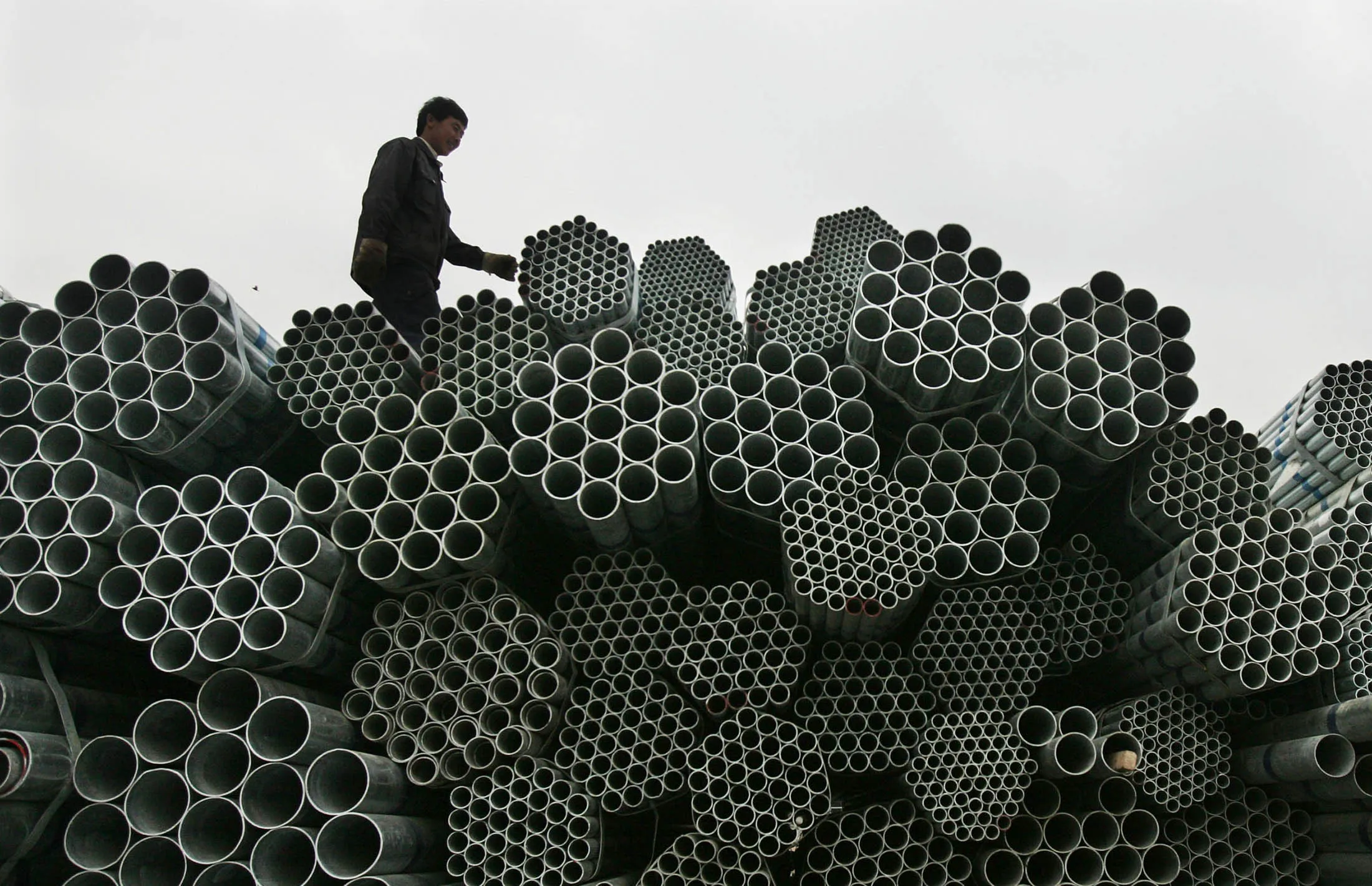 WUHAN, CHINA - APRIL 10: (CHINA OUT) A worker walks atop a pile of steel tubing at a steel product market on April 10, 2008 in Wuhan of Hubei Province, China. China's steel prices have surged 10 percent this year, and increased 23 percent in March compared with the same time last year, according to statistics from China Iron and Steel Association (CSIA). Since more steel products are required for reconstruction after the recent snow disaster and rising investment in real estate, the gap between demand and supply will be further widened.
