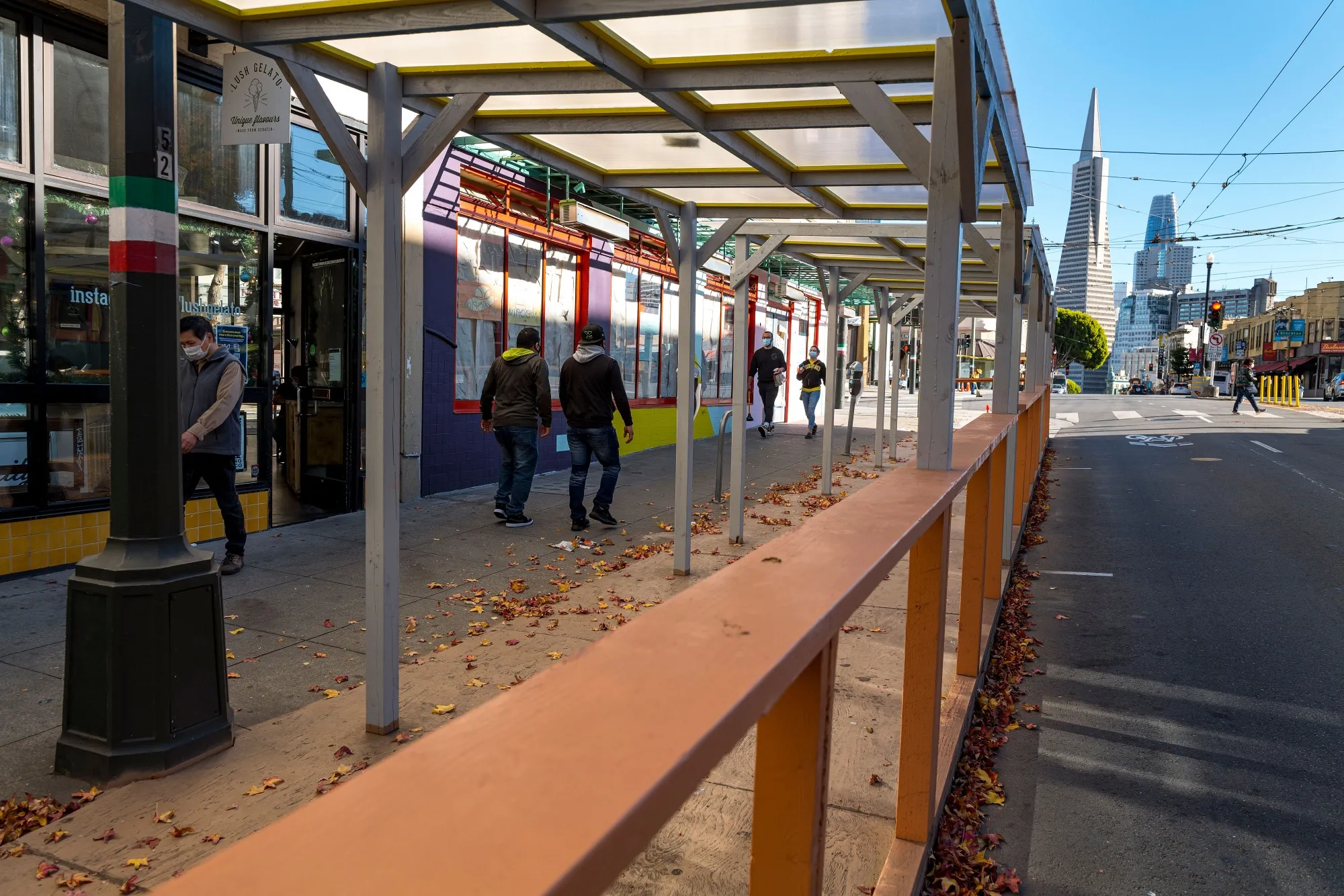 Pedestrians walk past an empty outdoor seating area at a restaurant in San Francisco.