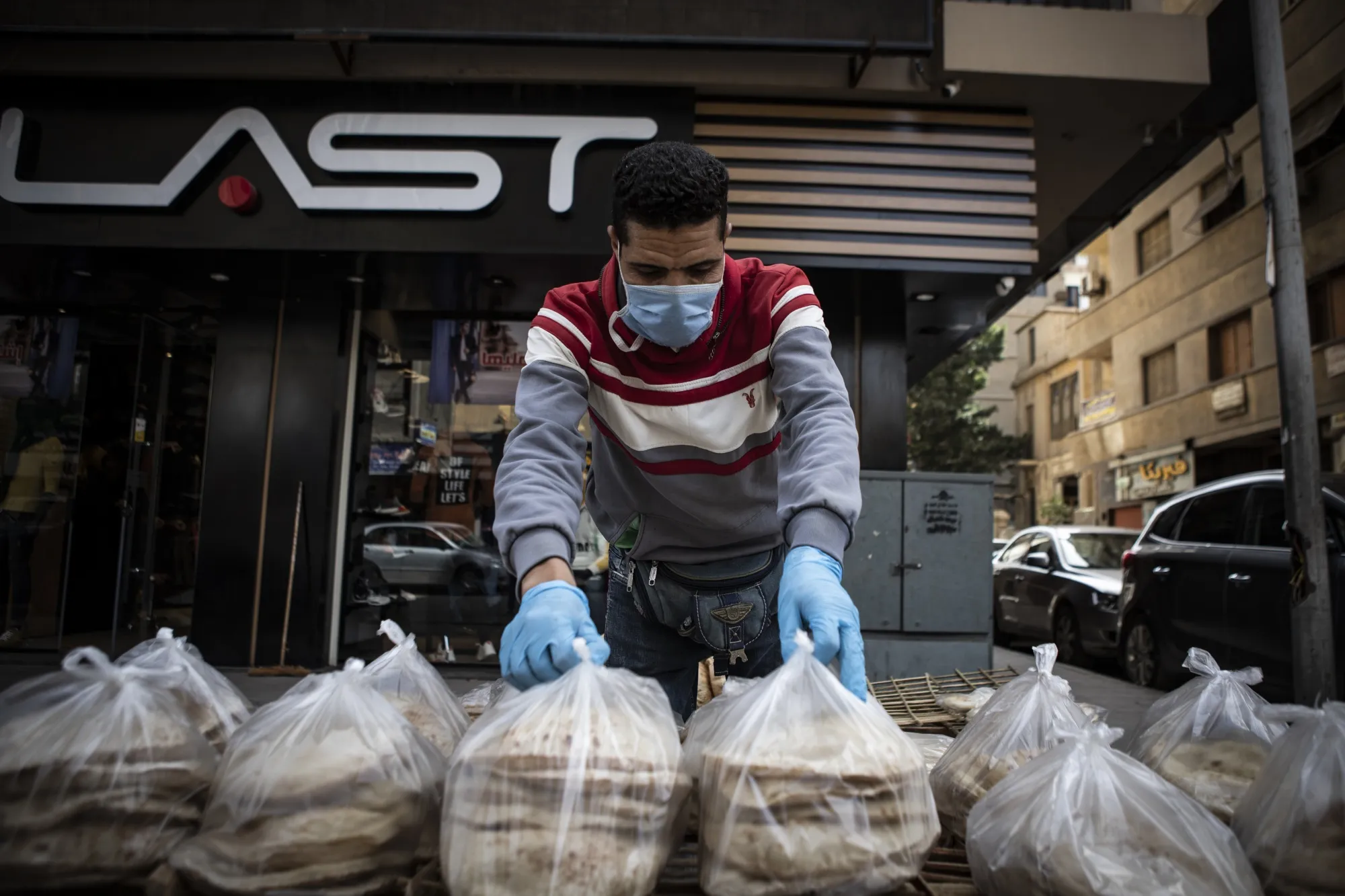 An vendor wearing a protective mask and gloves sorts bread for sale in Cairo on March 30, 2020.