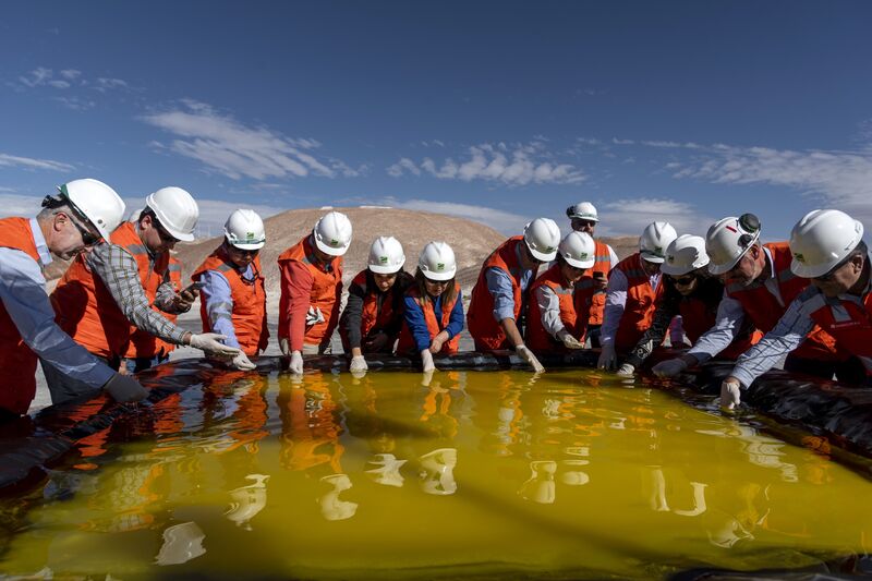 Visitors inspect a brine pool at a Sociedad Química y Minera de Chile (SQM) lithium mine on the Atacama salt flat in the Atacama Desert, Chile on May 29, 2019.