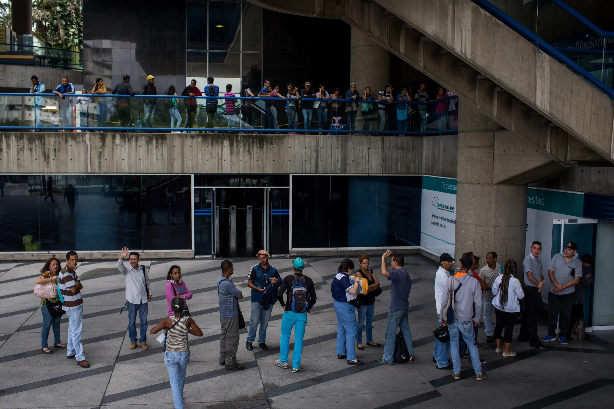 People wait in line to withdraw new sovereign bolivar banknotes at bank branches in Caracas, Venezuela