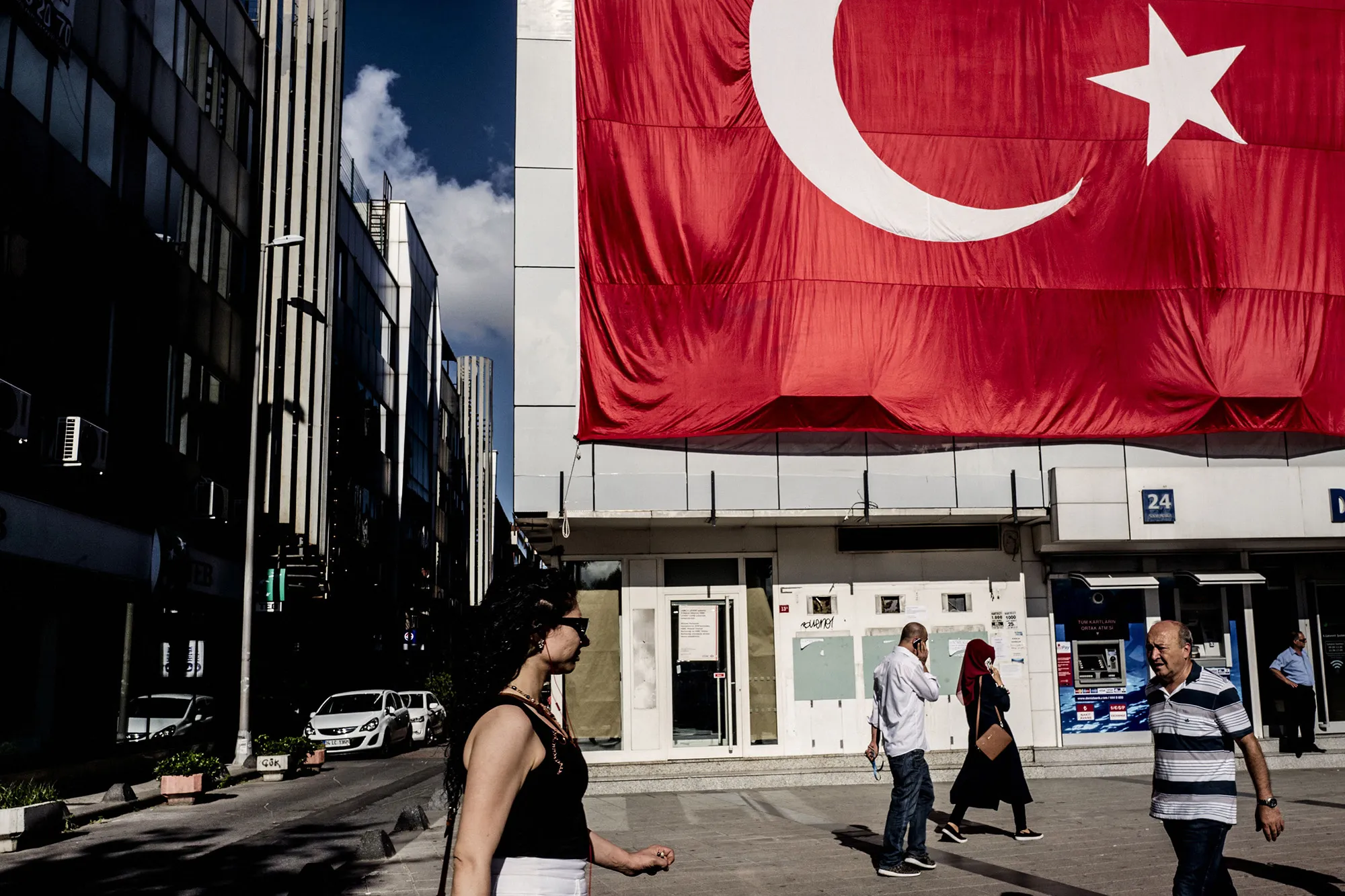 Pedestrians pass a giant Turkish national flag hanging above a DenizBank AS bank branch in Istanbul, Turkey, on Tuesday, July 19, 2016.