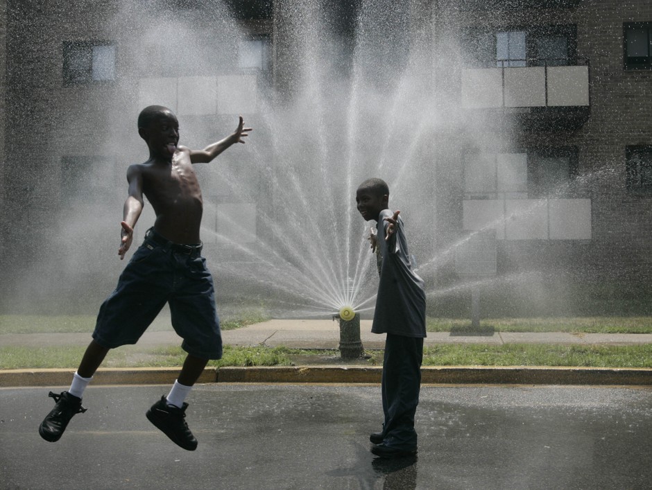 Two kids play in the spray from a fire hydrant during a D.C. heat wave. 