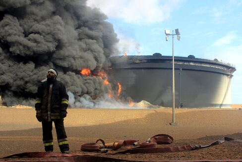 A fireman stands in front of damaged oil storage tanks near the Ras Lanuf oil terminal in January.