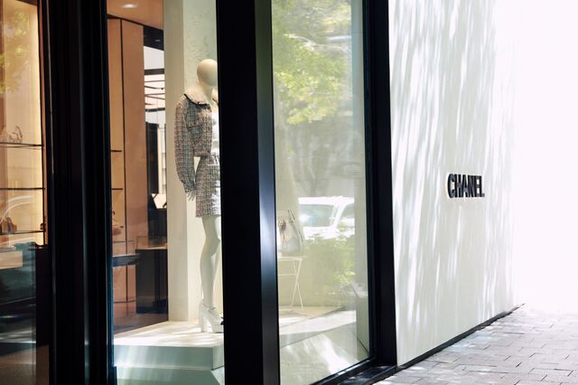 The exterior of a Chanel fashion boutique with a manequin dressed in a shirt and jacket. 