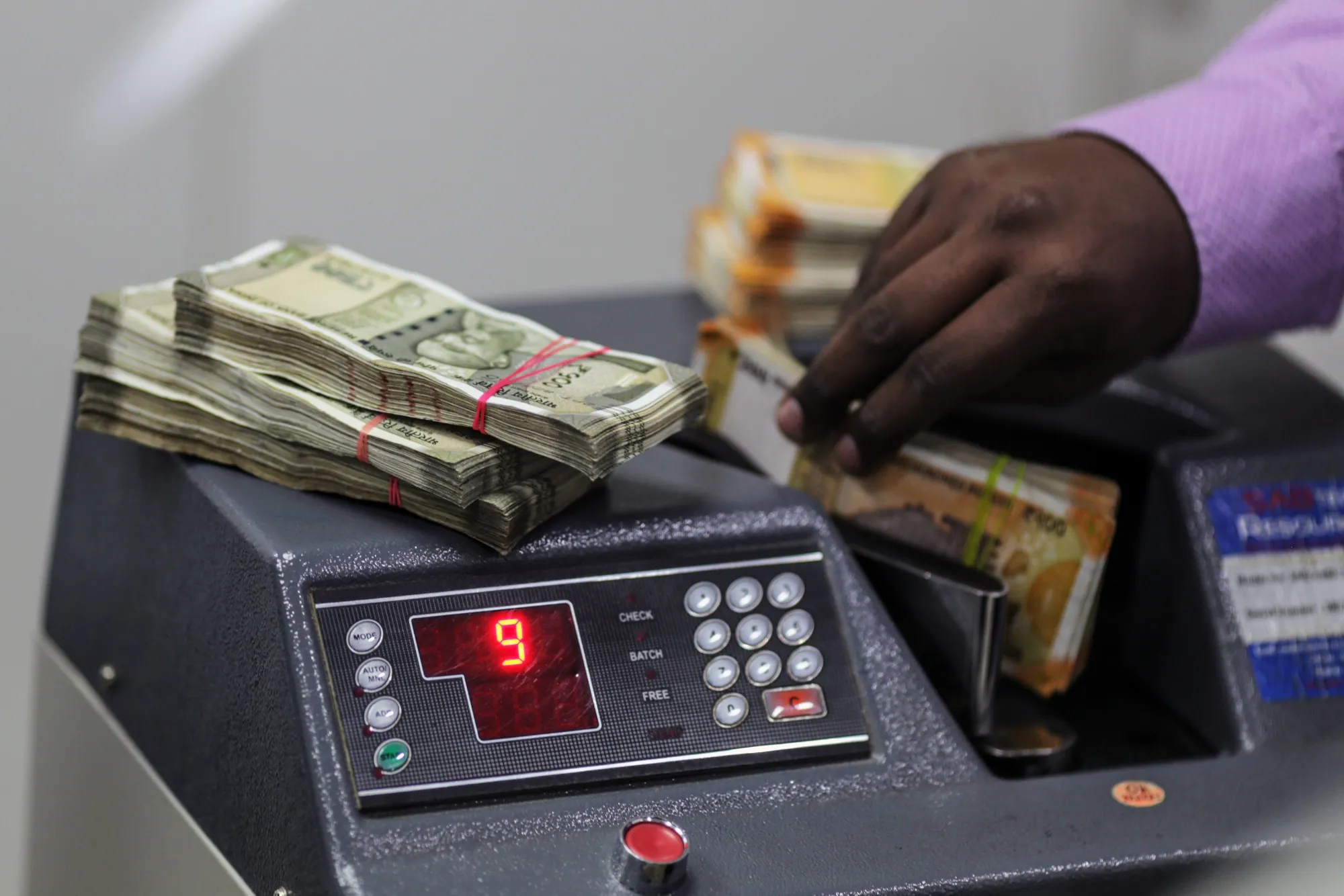 A HDFC Bank teller counts Indian 200 rupee banknotes in Mumbai.