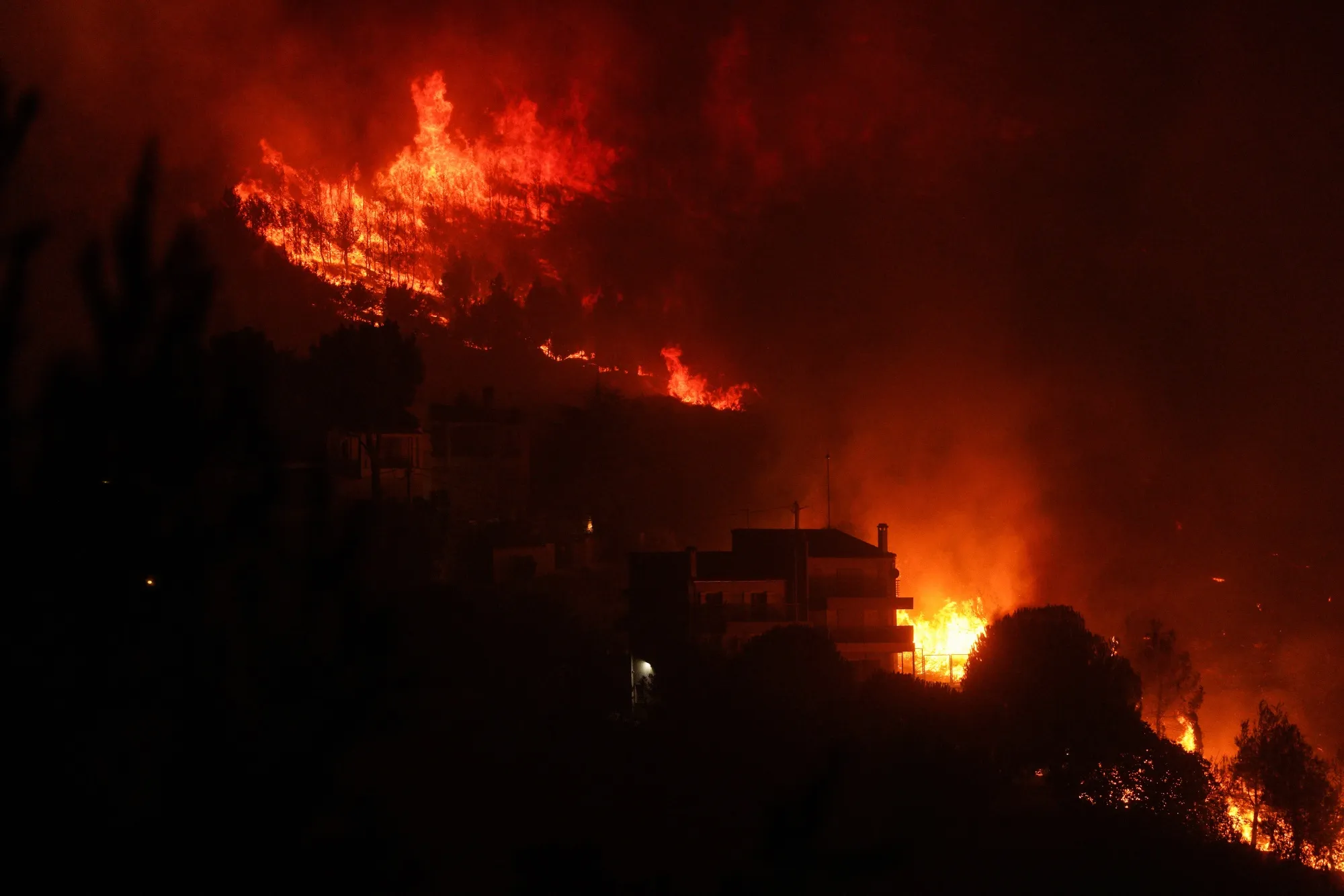 Flames from a wildfire threaten properties in Dionysos, Greece, on Aug. 12.