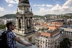 A tourist looks out across city rooftops from a viewing area at St. Stephen's Basilica in Budapest, Hungary.