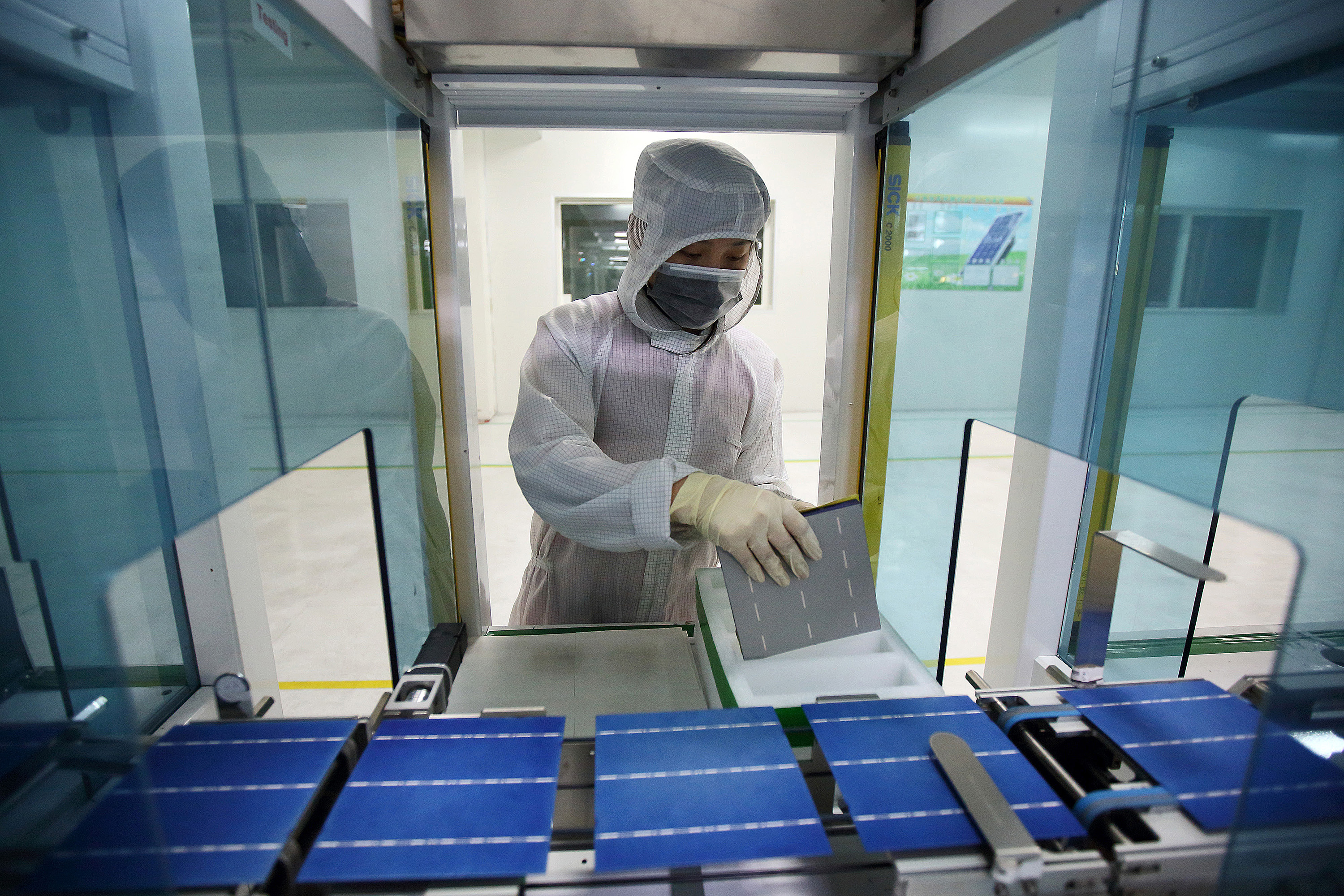 An employee inspects solar cells moving along the production line at the Trina Solar Ltd. factory in Changzhou, Jiangsu Province, China. Photographer: Tomohiro Ohsumi/Bloomberg
