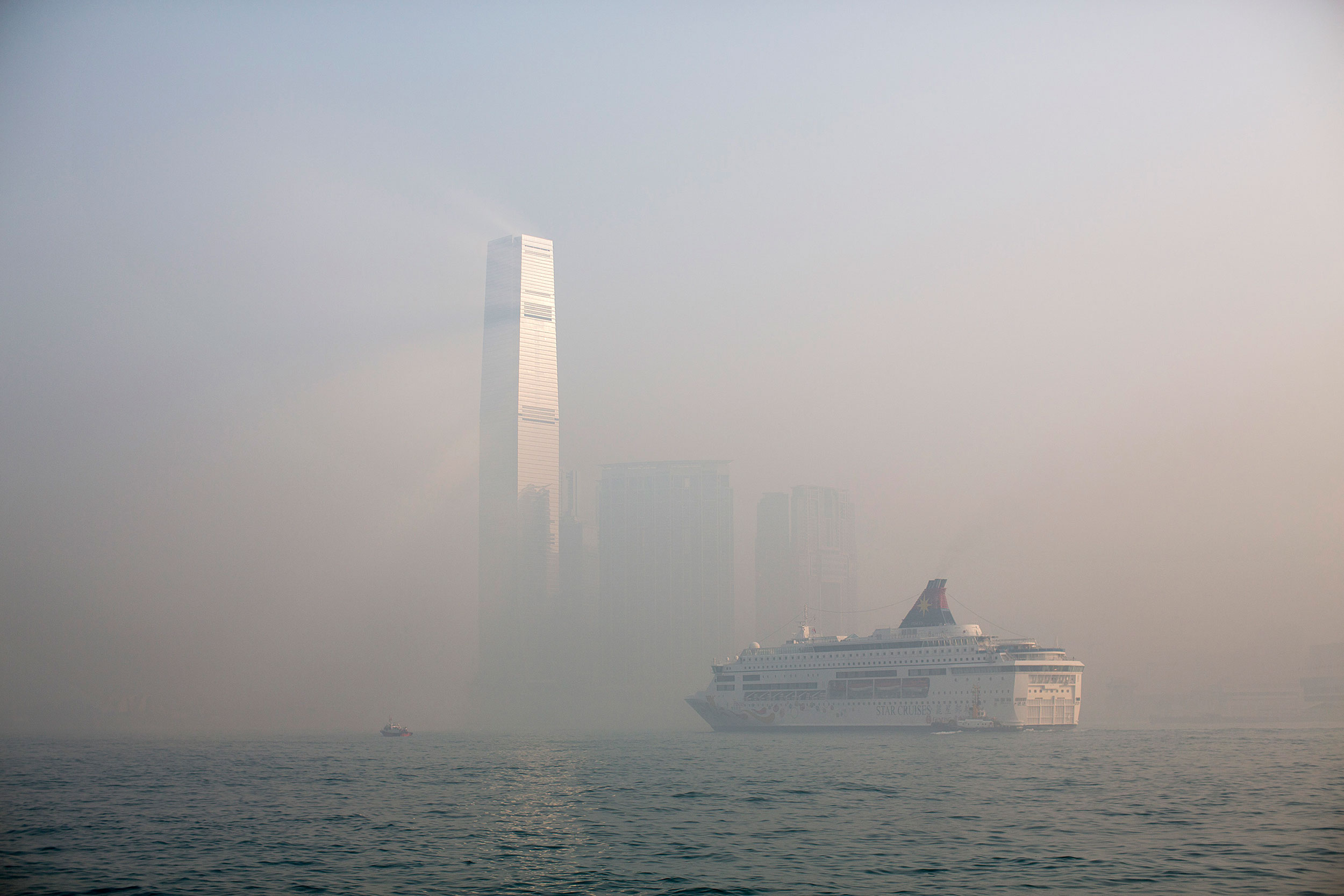 Haze surrounds the International Commerce Centre (ICC), center, as a cruise ship sails past in Hong Kong,.
