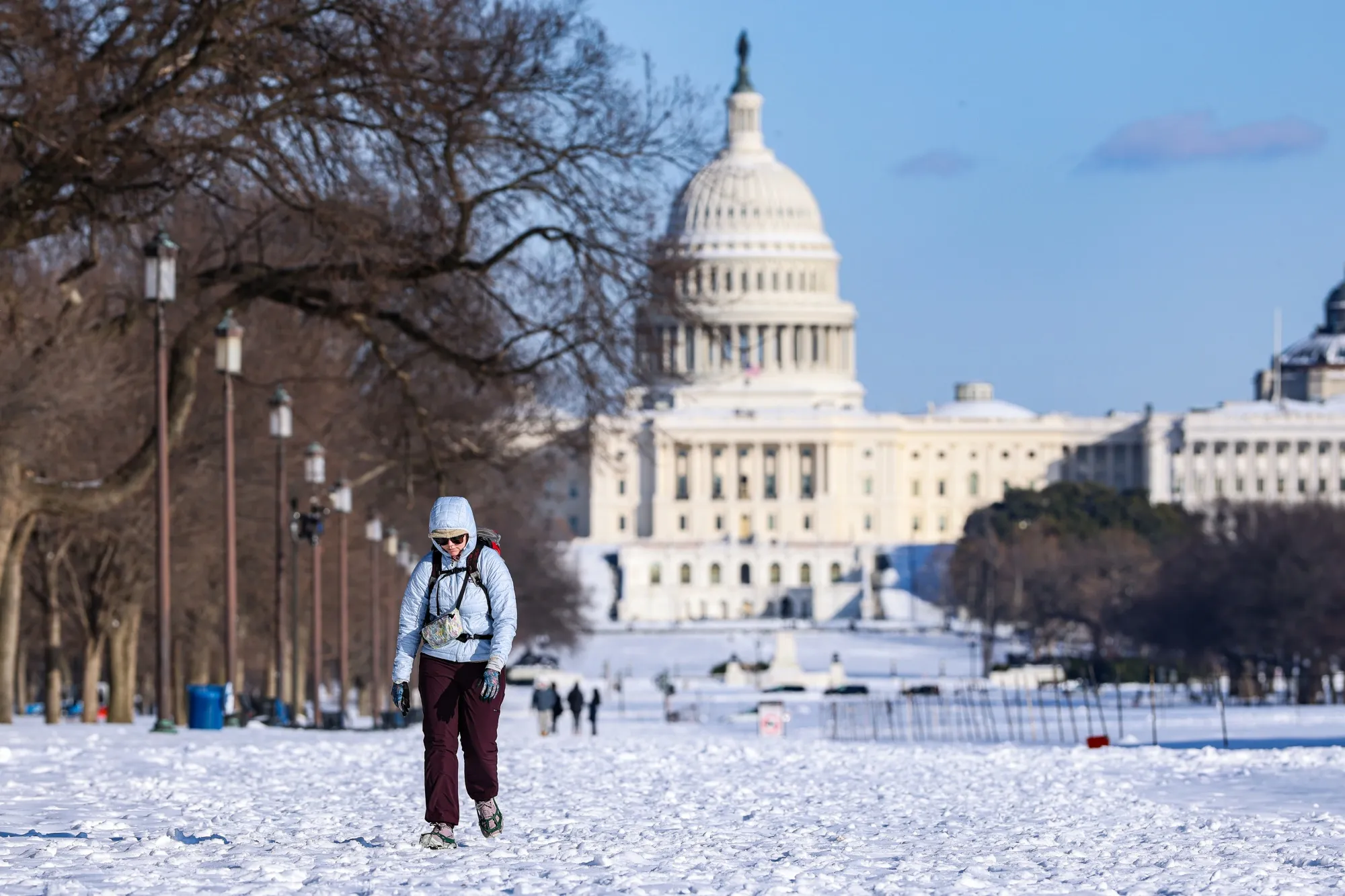 The US Capitol behind a pedestrian on the National Mall in Washington, DC.